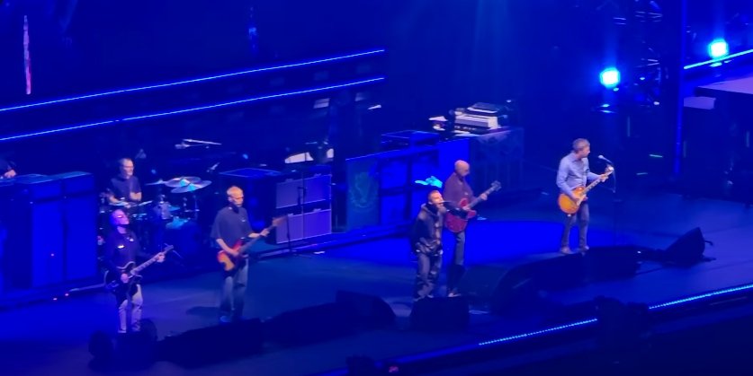 Oasis tocando en vivo en 2025 sobre un escenario azul